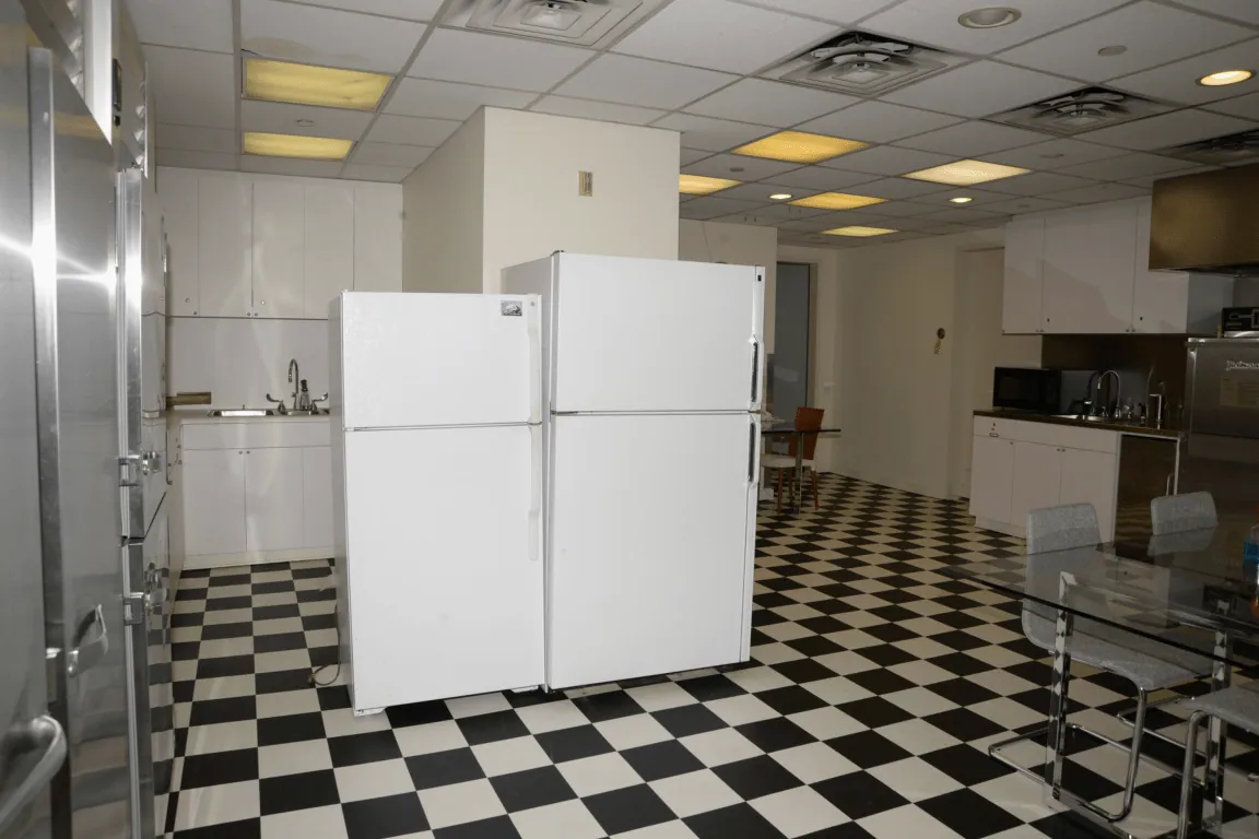 EFTA00000389 - Kitchen with white cabinets two large refrigerators on the black-and-white checkered floor and a dining table with chairs